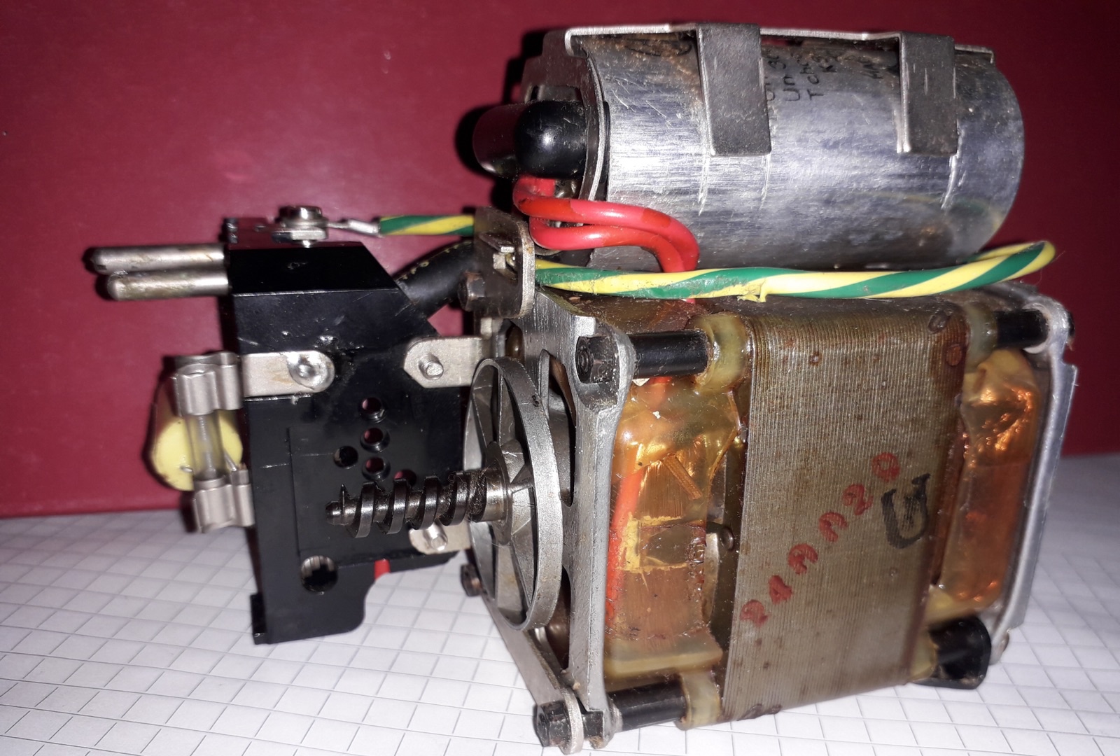 Single-phase motor assembly with a cylindrical capacitor mounted above the windings and connected by red wires.