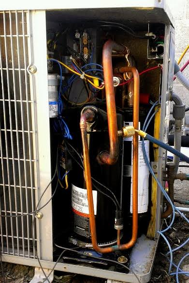 HVAC compressor and copper refrigerant lines inside an outdoor condensing unit